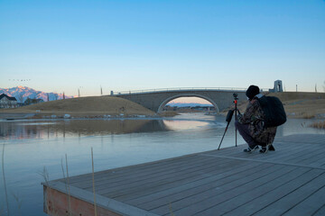 Wall Mural - Docks of a river where a person is on it and taking a record of the place with a tripod.