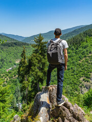 young guy looks into the distance at the green mountains. backpacker man looking into the distance o
