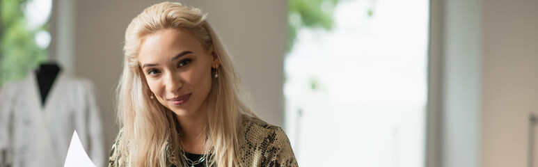 stylish fashion designer smiling at camera in tailor house, banner