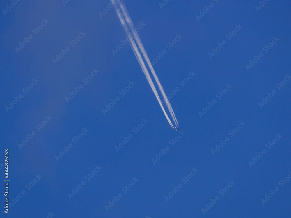 Smuga kondensacyjna na niebieskim niebie po przelocie samolotu. - obrazy, fototapety, plakaty 