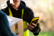 © Martin Barraud/Caia Image - Close up courier with smart phone delivering package