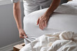 Woman is putting on a fitted sheet on a mattress while making the bed