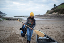 Young Woman With Oars At Canoe On Winter Beach