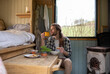 © Sam Edwards/Caia Image - Young man eating and drinking in tiny cabin rental