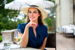 © elnariz - Lifestyle portrait headshot of a beautiful and elegant caucasian woman sitting at a patio cafe outside, near a countryside park or vineyard winery, drinking a glass of wine