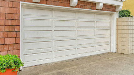 Pano White door of two car garage of home with shingle cladding on the exterior wall