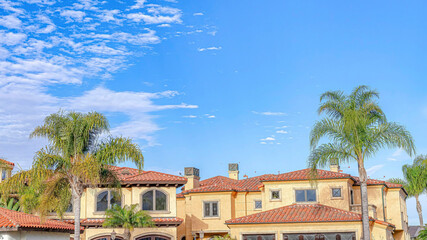 Wall Mural - Pano Blue sky with clouds with home and palm trees in Huntington Beach California