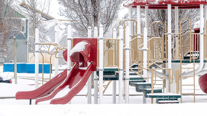 Wall Mural - Pano Park on a scenic neighborhood with colorful playground on a snowy winter setting