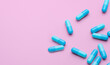 Blue antibiotic capsule pills spread on pink background. Antibiotic drug resistance. Pharmaceutical industry. Healthcare and medicine concept. Health budget concept. Capsule manufacturing industry.
