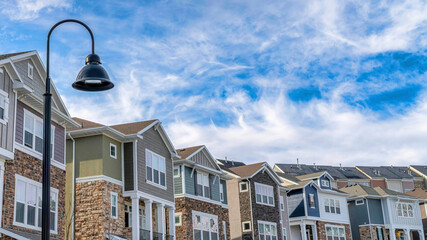 Wall Mural - Pano Homes and lamp post against blue sky and clouds on sunny neighborhood landscape