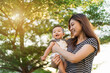 © geargodz - happy mother holding newborn baby in a tender embrace on green nature bokeh background with sunlight