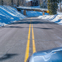 Wall Mural - Square Snowy mountain road with homes and evergreens viewed from inside a vehicle