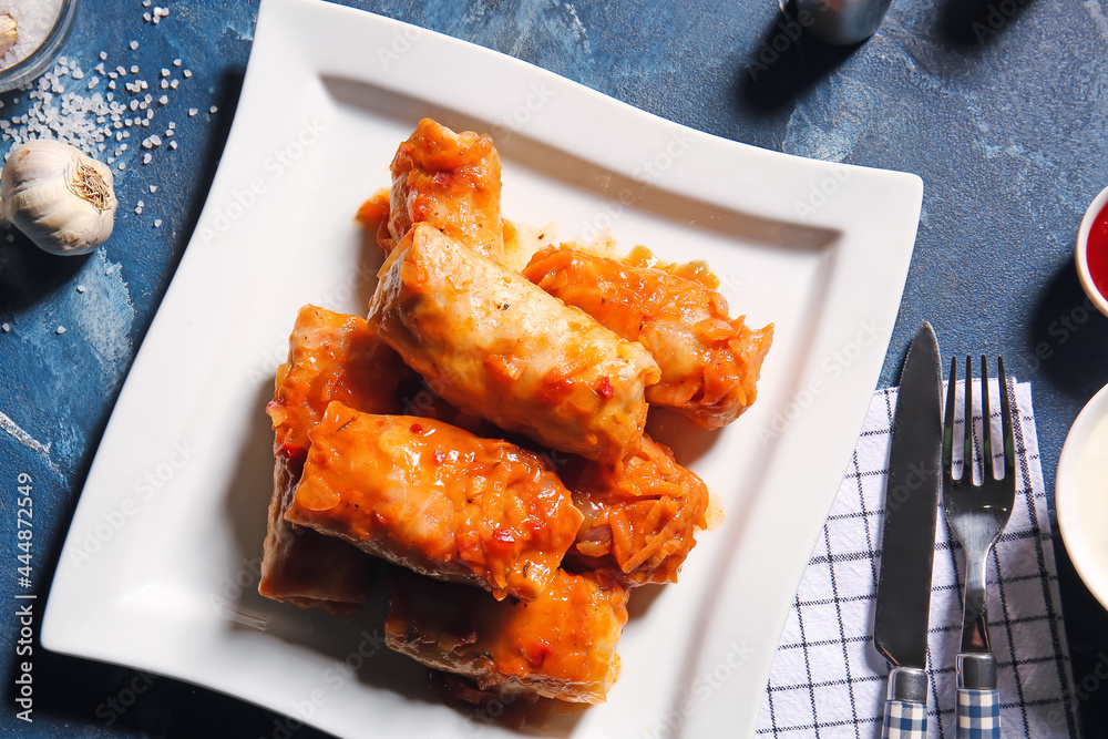 Plate with tasty stuffed cabbage rolls on color background
