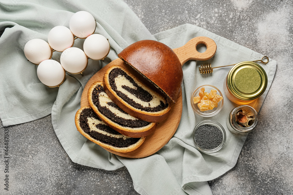 Wooden board with tasty cut poppy seed bun on table