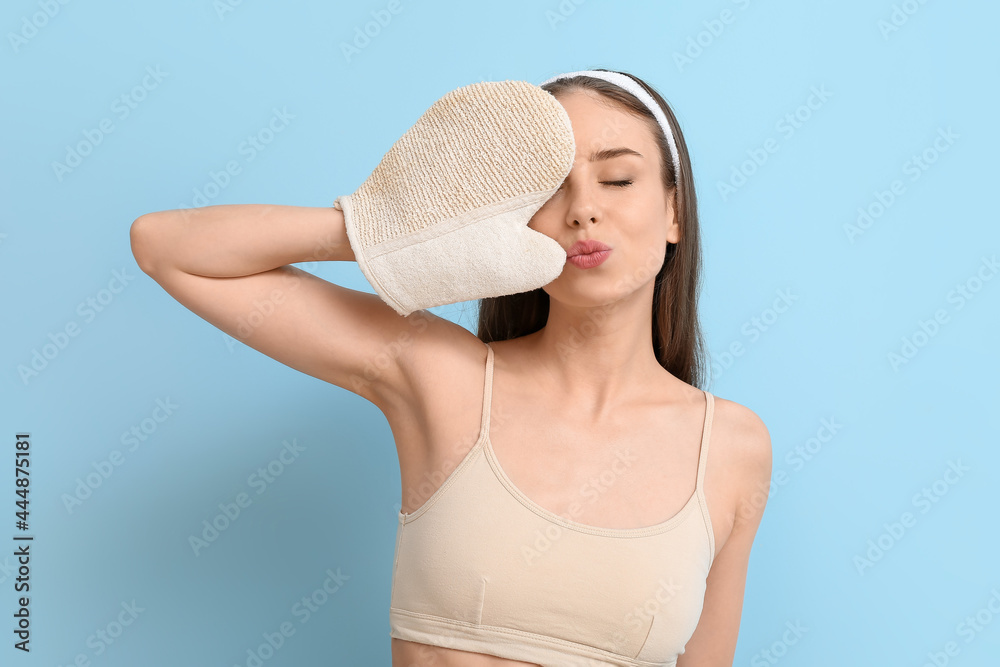 Beautiful young woman with massage mitten on color background