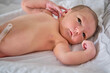 © Андрей Журавлев - A newborn baby in a diaper is lying naked on the bed. Child boy in a cocoon on a cot.
