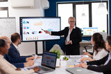 Fototapeta  - Senior startup businesswoman holding presentatin in conference room briefing, graph, information. Corporate staff discussing new business application with colleagues looking at screen