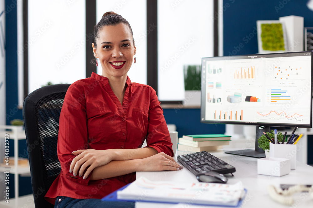 Portrait of business woman in corporate office sitting at desk smiling at camera. Company executive leadership working on financial statistics. worker doing charts on computer. - obrazy, fototapety, plakaty 