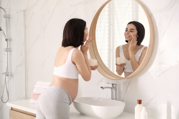 Poster - Young pregnant woman with cosmetic product in bathroom