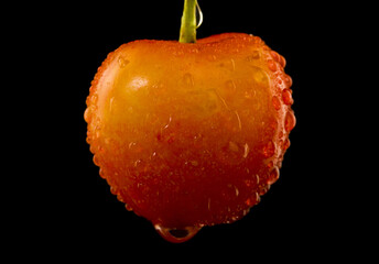 Poster - Red yellow cherry in drops of water isolated on black background.