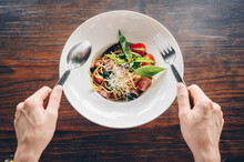 Table Top View Of Woman Trying To Eat Spaghetti With Knife And Fork. Spaghetti Is One Of The Most Popular Forms Of Pasta, And It's Used In Dishes All Around The World, Is Fairly Neutral, Diet.