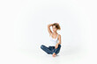 © SHOTPRIME STUDIO - woman in white t-shirt and jeans sits on the floor holding her hair