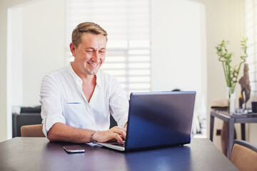 Handsome caucasian man using laptop sitting at his desk in the office