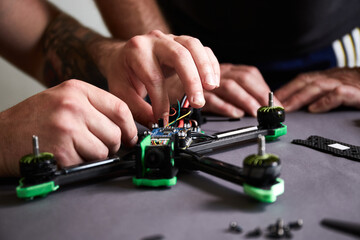 Close up of man's hands assembling a drone from parts, using tools, Preparing high-speed racing quadcopter for flight. Repair drone before training process.