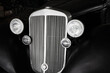 Detail of retro car. Radiator grille and headlight lamp on vintage car