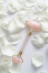 Wall Mural - Face massage tool roller with rose petals on white background. Flat lay, top view.