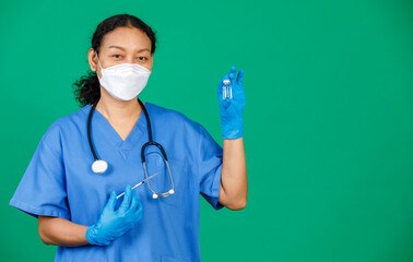 Asian female nurse in scrubs wearing mask holding syringe and Covid 19 vaccine preparing for injection. Concept for Covid 19 vaccination