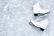 White Female Figure Skates On Ice Background. Sport Accessories For Outdoor Activities In Cold Winter Season. Closeup. Empty Place For Text. Top Down View.
