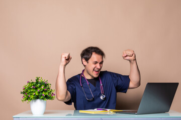 Young man doctor with fist up celebrate victory sitting in the office