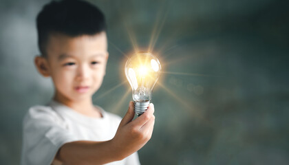 Poster - Boy kid Child with a bright light bulb. Concept of Ideas for presenting new ideas Great inspiration and innovation new beginning.