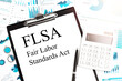 © Krystsina - Text FLSA - Fair Labor Standards Act on clipboard, pen, calculator, charts. Business concept. Flat lay.