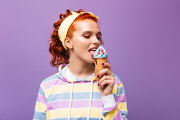 Sticker - Girl in striped sweatshirt and hairband poses on purple background and holds blue ice cream