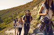 © Studio Romantic - A group of tourists with backpacks on a hike in nature. Friends are walking on a hill in the mountains. Hiking in the summer.
