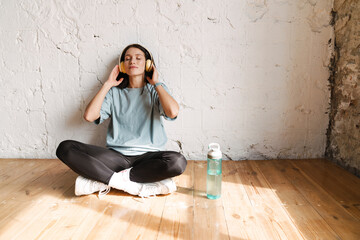 Wall Mural - Smiling young white sporty woman in earphones