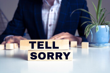 Wall Mural - An image of letter imprinted wood blocks displaying the words - TELL SORRY.