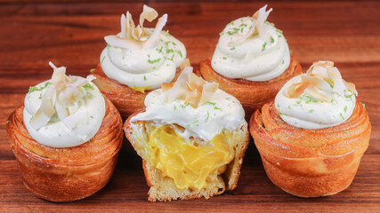 Canvas Print - A close up of aligned cruffins with cream on the top on brown wooden surface