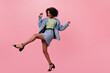 © Look! - Girl in skirt and jacket moves on pink background. Joyful african woman in denim suit dancing and has fun on isolated backdrop
