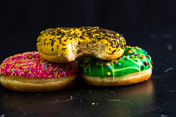 Sticker - Tasty colored donuts with sprinkles on a black background