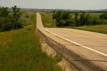 Paved two lane road leading away from congestion and into the peaceful countryside of rural America such as this scene in North Dakota.