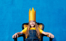 Cheerful Teenager In Paper Crown Sitting On Throne
