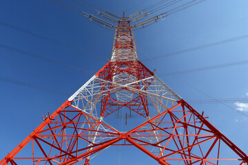 High-voltage electricity transmission tower under blue sky and white clouds . Power lines against the sky