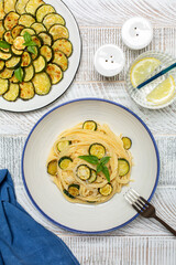 Poster - Italian lunch. Pasta with roasted zucchini and parmesan cheese on white wooden table. Top view, vertical image.