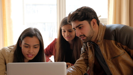 Poster - Closeup view of a group of friends looking at something through a tablet at an apartment