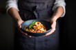 © The Picture Pantry - A blue bowl of pasta and tomato sauce held by a cook