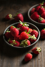 Strawberries In Dark Bowls On Wood Background