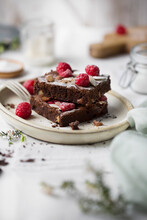 Brownies With Almonds And Raspberries On A White Plate